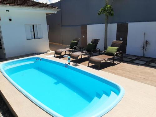 a large blue swimming pool in a patio with chairs at Pousada Praia Cia, Piscina, Centro, Estacionamento, WIFI, Saída até as 16h in Bertioga