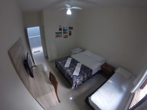 um pequeno quarto com uma cama e uma janela em Pousada Praia Cia, Piscina, Centro, Estacionamento, WIFI, Saída até as 16h em Bertioga