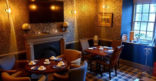 a dining room with two tables and a fireplace at Garth Hotel in Grantown on Spey