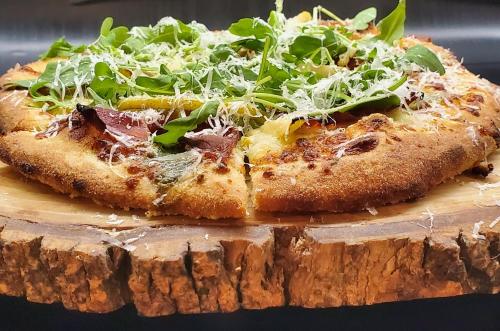 a pizza sitting on top of a wooden cutting board at Inn at the Falls in Bracebridge