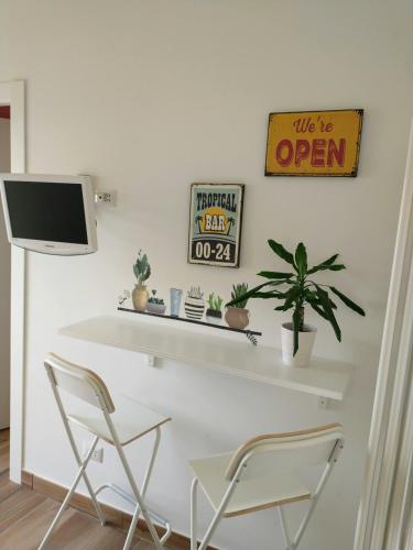 een wit bureau met 2 stoelen en een tv aan de muur bij Mi casa tu casa in Formia