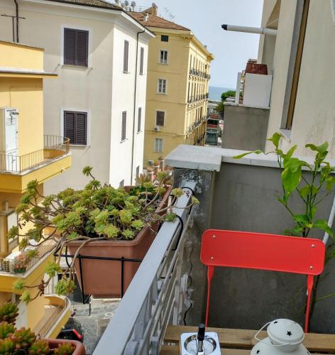 einen Balkon mit Topfpflanzen und einem roten Stuhl in der Unterkunft Mi casa tu casa in Formia