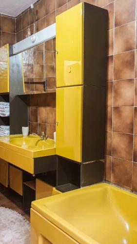 a yellow bathroom with a sink and a mirror at Planinska kuća za odmor Vuković in Podgrab