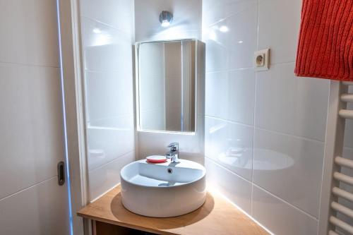 La salle de bains est pourvue d'un lavabo blanc et d'un miroir. dans l'établissement La Station - Lourdes - Centre - Residence Serenity, à Lourdes