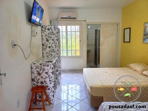 a bedroom with a bed and a tv on a wall at Pousada São Francisco in Florianópolis