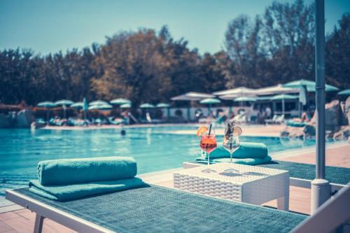 einen Tisch mit 2 Stühlen und einen Pool in der Unterkunft Resort Tenuta Primero in Grado
