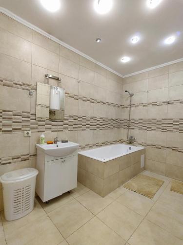uma casa de banho com uma banheira, um lavatório e um WC. em Уютная квартира с панорамой города em Odessa