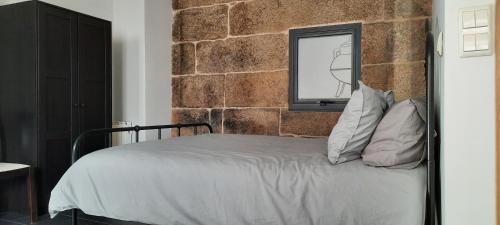 ein Schlafzimmer mit einer Ziegelwand und einem Bett mit Kissen in der Unterkunft Casas da Bríxida. Primeiro in Cangas