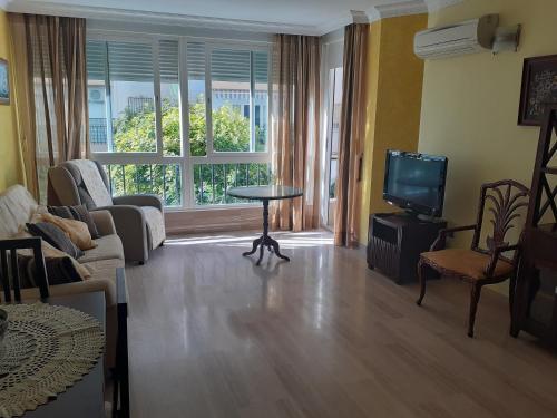 een woonkamer met een bank, een tv en een tafel bij Albaida II Bajo G Apartamento Nerja in Nerja