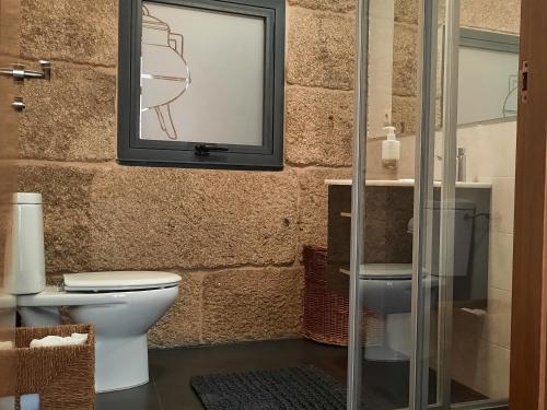 a bathroom with a toilet and a tv on the wall at Casas da Bríxida. Primeiro in Cangas de Morrazo