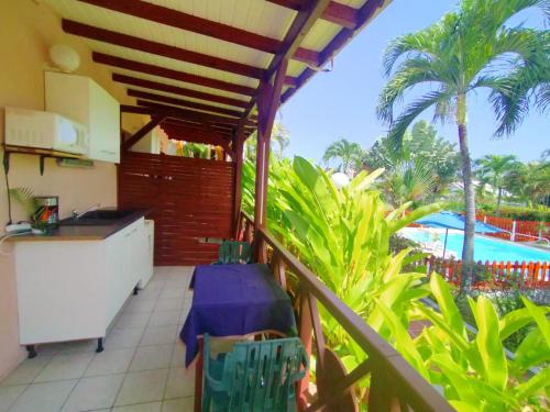 balcón con cocina y vistas a la piscina en Bungalow charmant à Sainte-Rose, piscine partagée, en Sainte-Rose