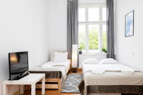a living room with two beds and a tv at Baltic Rooms Sopot in Sopot