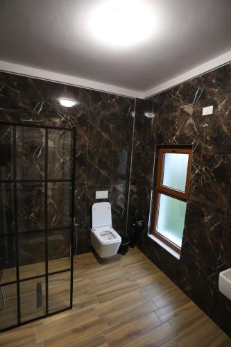 a bathroom with a toilet and a window at House of Horses Shtepia e Kuajve in Korçë