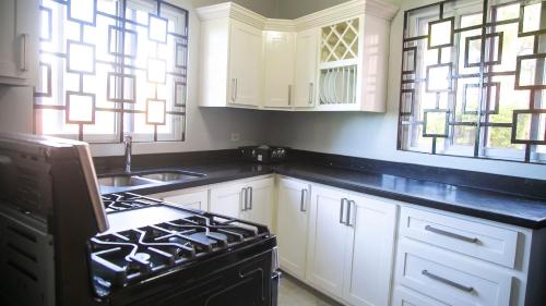 a kitchen with white cabinets and a stove and windows at Ocean View Terrace in Montego Bay