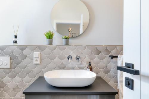 a bathroom with a white sink and a mirror at One Moment Boardinghouse - Apartment Forest in Porta Westfalica