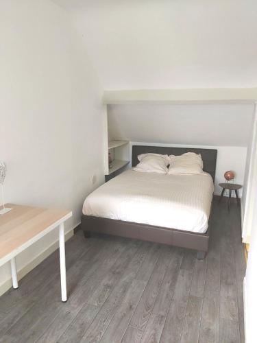 a white bedroom with a bed and a table at Le Berry - Maison de ville - Parking privé in Bourges