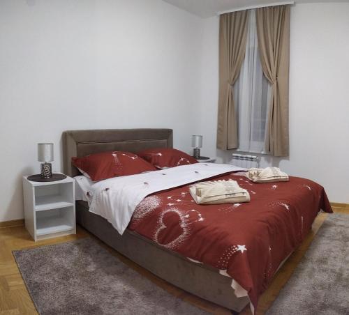 Schlafzimmer mit einem Bett mit roter Bettwäsche und einem Fenster in der Unterkunft Apartman Davidović 31 in Valjevo