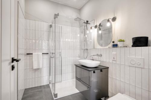 La salle de bains blanche est pourvue d'un lavabo et d'une douche. dans l'établissement Apartment Cozy, à Porta Westfalica