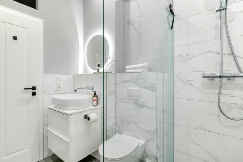 a white bathroom with a shower and a toilet and a sink at Apartment Homely in Porta Westfalica