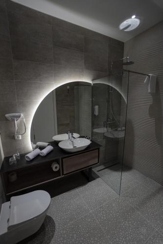 a bathroom with a sink and a toilet and a mirror at Hotel President in Čapljina