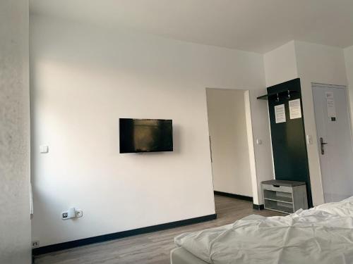 1 dormitorio con una pared blanca y TV. en Ferienwohnung am Geroweiher Mönchengladbach, en Mönchengladbach