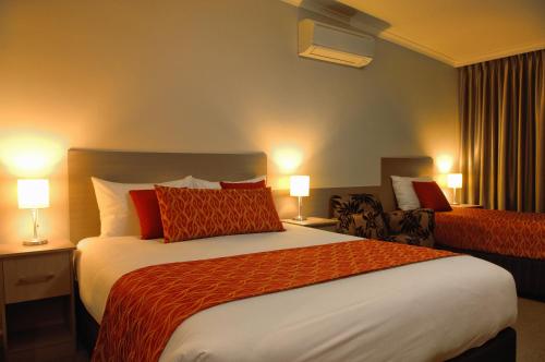 a hotel room with a large bed with red pillows at Tower Motor Inn in Mount Gambier