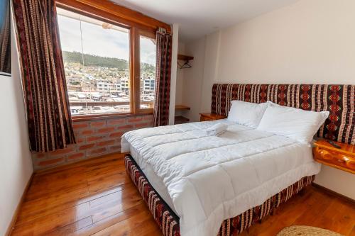 1 dormitorio con cama y ventana grande en Los Ponchos Inn Apartotel en Otavalo