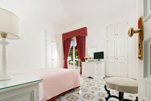 a white bedroom with a pink bed and a chair at Hotel Canasta in Capri