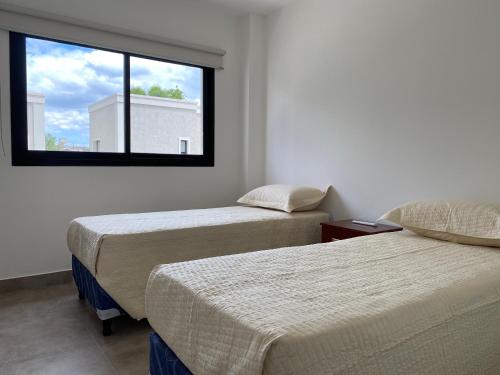 2 Betten in einem Zimmer mit Fenster in der Unterkunft La Escondida Salta 11 in Salta