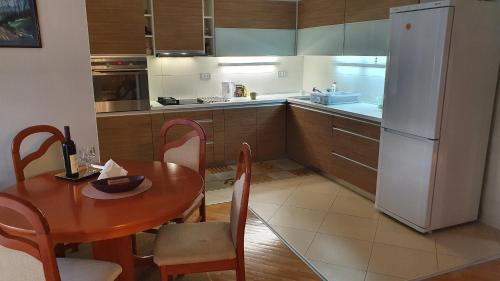 a kitchen with a wooden table and a white refrigerator at Broj jedan Delux in Soko Banja