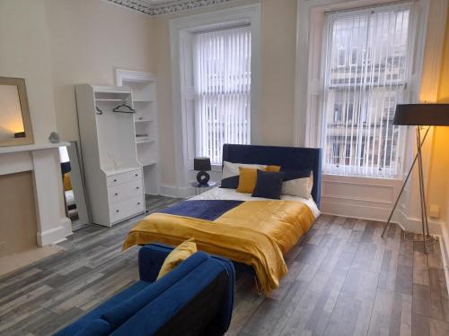 a bedroom with a bed and a couch and windows at Traditional west end Glasgow in Glasgow