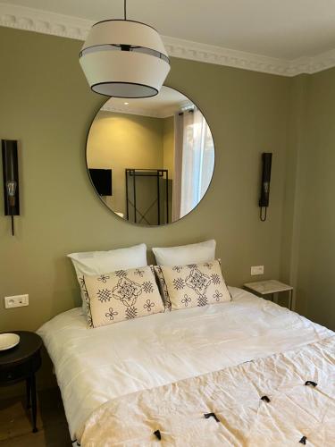 a bedroom with a large white bed with a mirror at Le Grand Albert 1er in Maisons-Alfort
