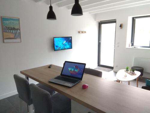 a laptop sitting on a wooden table in a room at Maison Cosy entre CAP FREHEL et SAINT MALO 1km PLAGE 5min GR34 Wifi Jardin Vélos "CASA OHANA" in Saint-Cast-le-Guildo