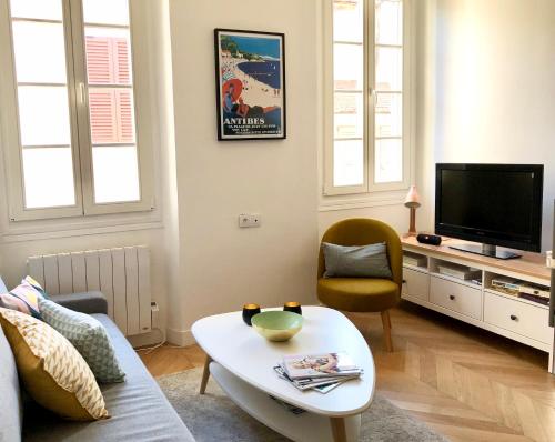 ein Wohnzimmer mit einem Sofa und einem TV in der Unterkunft Charming and modernly designed 2 bedroom - Old Town in Antibes