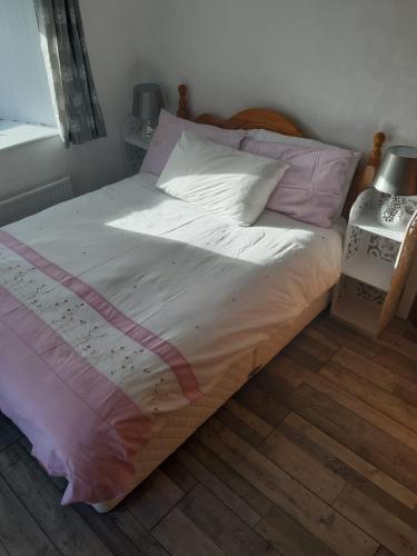 uma cama com lençóis e almofadas cor-de-rosa e brancos em Clare's Cottage em Miltown Malbay