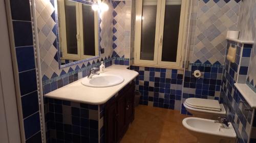 a blue tiled bathroom with a sink and a toilet at Bed and Breakfast Dorgali in Dorgali