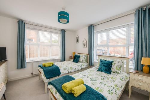 a bedroom with two beds and two windows at Spire View - New Forest Holiday Home in Lyndhurst