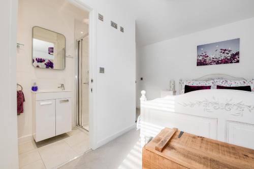 a white bathroom with a large bed and a mirror at Spire View - New Forest Holiday Home in Lyndhurst