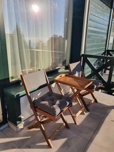two wooden chairs and a table on a balcony at Lux Apartman Lucky in Kopaonik