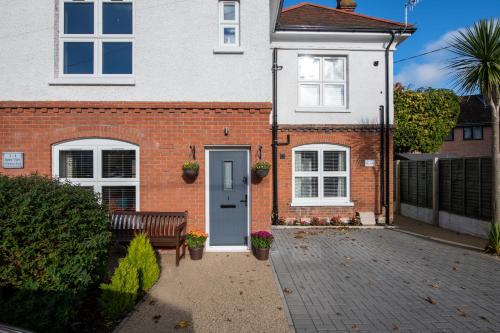 a brick house with a blue door and a bench at Spire View - New Forest Holiday Home in Lyndhurst