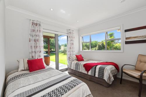 a bedroom with two beds and a window at Sunny on Sunlea - Mangawhai Village Holiday Unit in Mangawhai