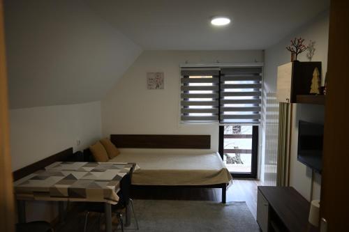 ein Schlafzimmer mit einem Bett und einem Tisch und einem Fenster in der Unterkunft Apartman Vukašin in Kopaonik