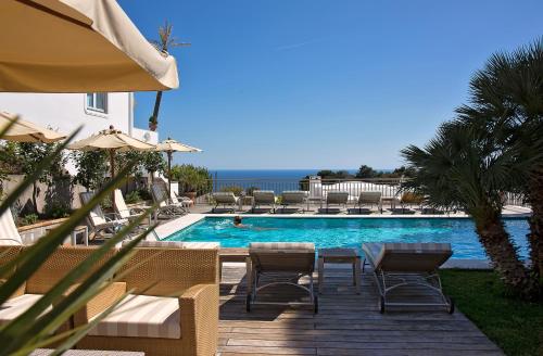een zwembad met stoelen, een tafel en een parasol bij Hotel Canasta in Capri