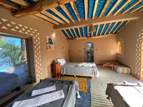 a bedroom with two beds and a large window at Camp Auberge Sahara Marokko in Mhamid