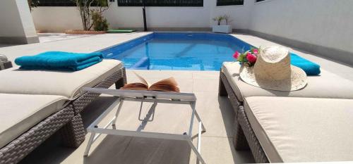 una piscina con 2 camas y una mesa con sombrero en CASA SOLEADA. Intimidad, piscina y mucho sol., en Santiago de la Ribera