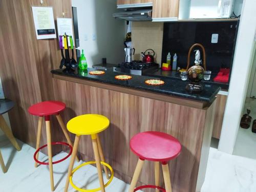 a kitchen with three colorful stools in front of a counter at Lindo Apartamento na Praia do Futuro in Fortaleza