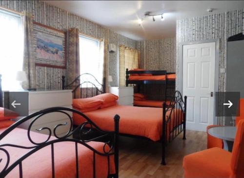 1 dormitorio con 2 camas con sábanas de color naranja y mesa en Fairhaven Hotel on Woodfield Road, en Blackpool