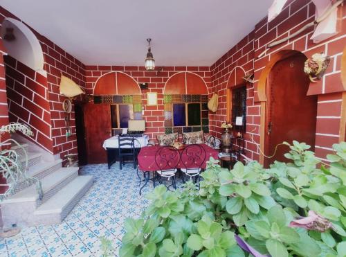 a red brick room with a table and chairs at Kasabah Senhaji in Moulay Idriss Zerhoun