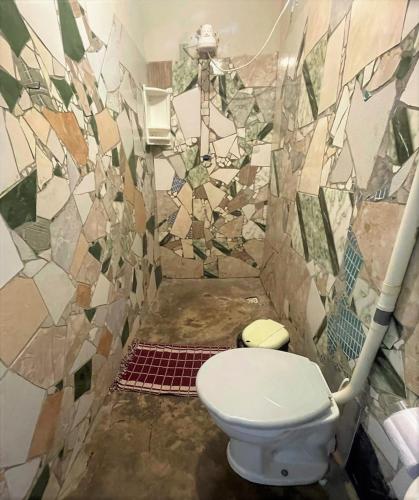 a bathroom with a toilet and a mosaic wall at Hostel do Ceu in Pipa