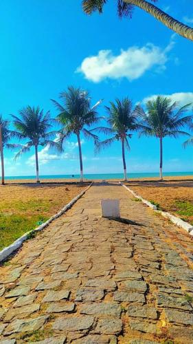 a stone road with palm trees on a beach at Japaratinga Suites in Japaratinga